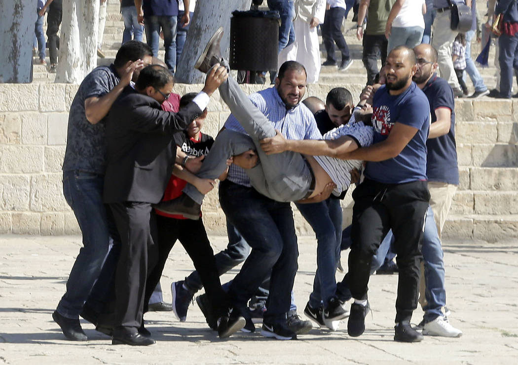 Palestinians carry injured person during clashes with Israeli police at al-Aqsa mosque compound ...