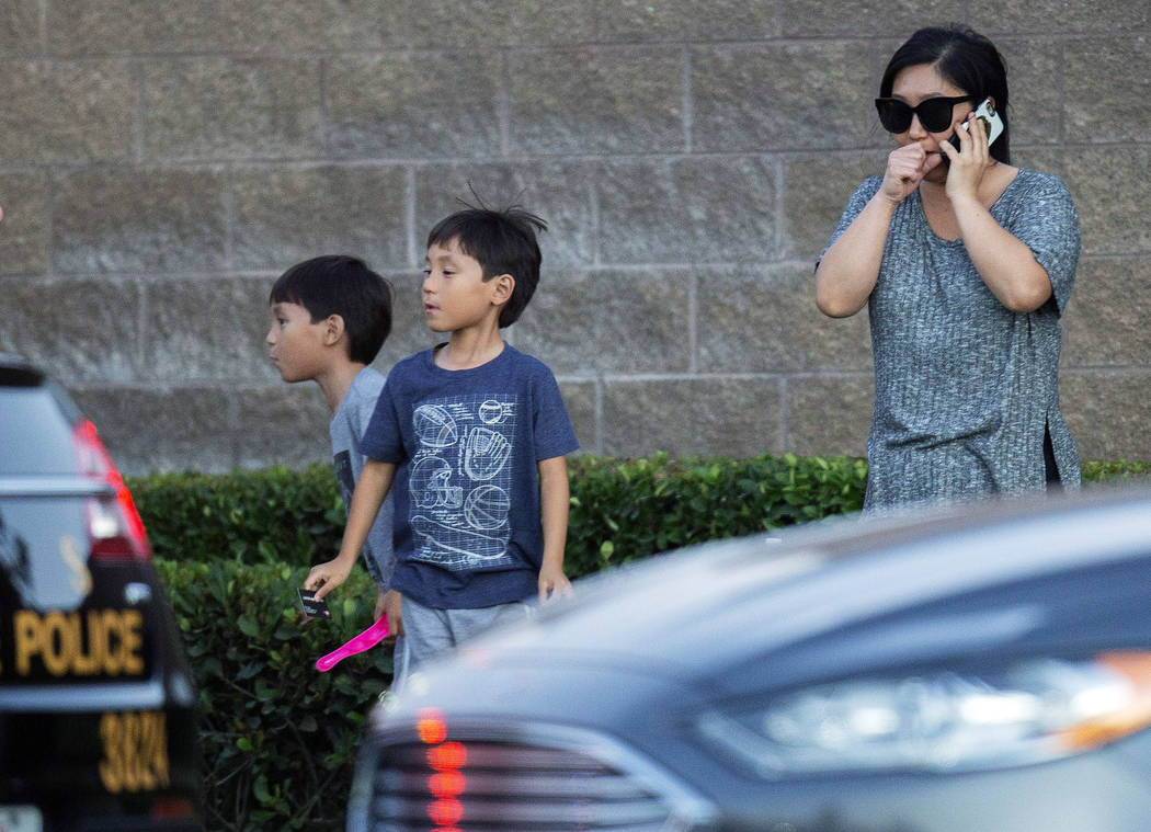 A woman and her two children stand near the scene where a shootout near a freeway killed a Cali ...