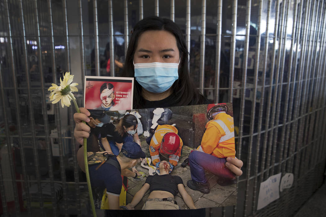 A woman holds a flower and posters showing people injured by police as protesters stage a sit-i ...