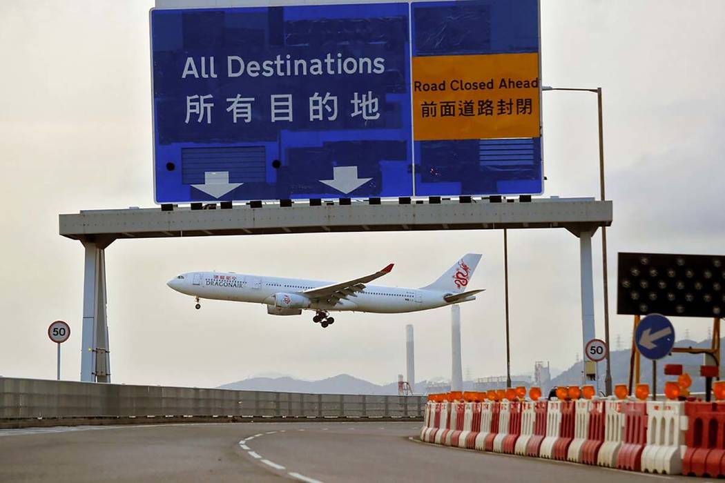 A Dragonair plane flies past a road sign at the airport in Hong Kong, Tuesday, Aug. 13, 2019. P ...