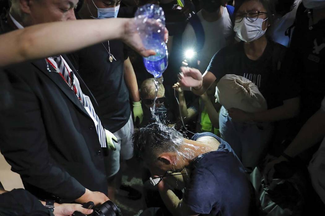 A protester pours water on a detained man, who protesters claimed was a police officer from mai ...