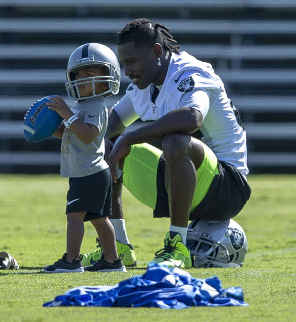 Oakland Raiders wide receiver Antonio Brown (84) plays on the sideline with his 23-month-old so ...