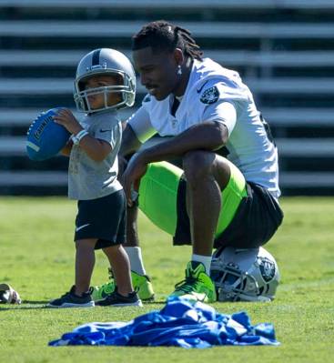 Oakland Raiders wide receiver Antonio Brown (84) plays on the sideline with his 23-month-old so ...
