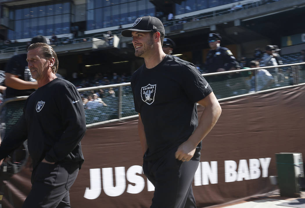 Oakland Raiders' Derek Carr, center, walks to the field prior to a preseason NFL football game ...