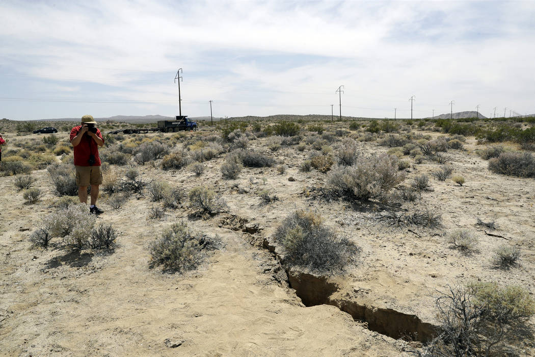 FILE - In this July 7, 2019 file photo, a visitor takes a photo of a crack in the ground follow ...