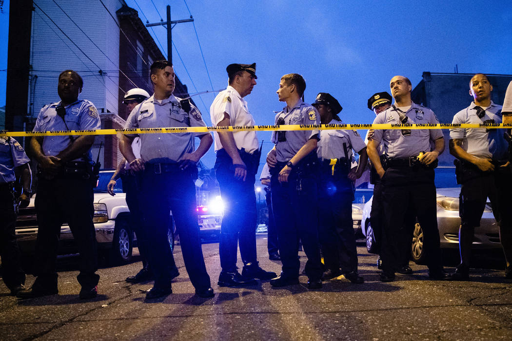 Officers gather for crowd control near a massive police presence set up outside a house as they ...