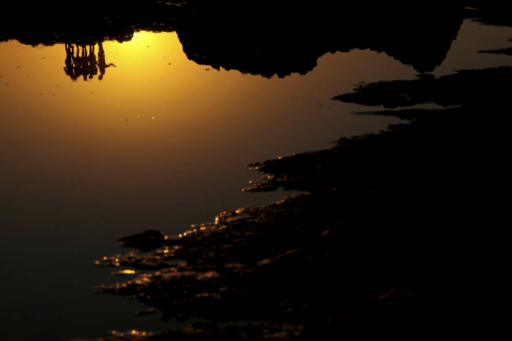 FILE - In this file photo dated Saturday, July 27, 2019, tourists are reflected in sea water af ...