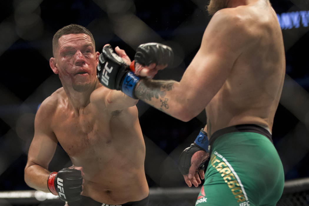 Nate Diaz, left, throws a punch against Conor McGregor in the welterweight bout during UFC 202 ...