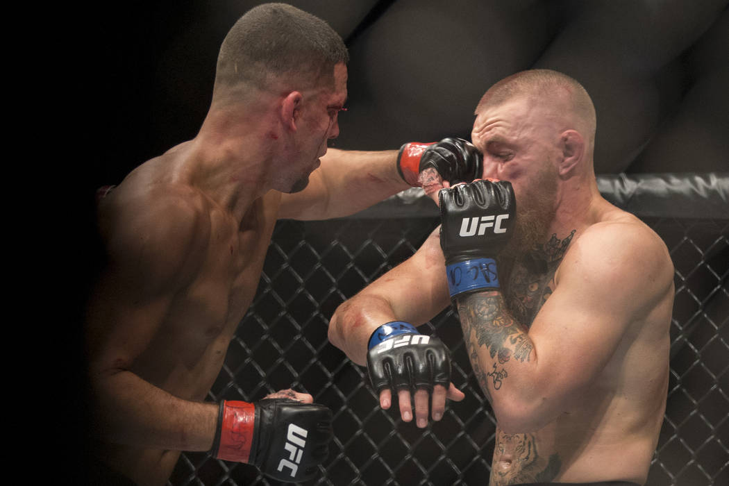 Nate Diaz, left, lands a left punch against Conor McGregor in the welterweight bout during UFC ...