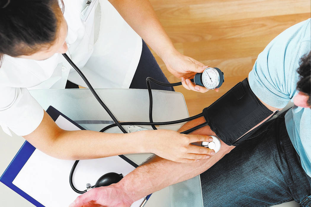 Close-up Of Female Doctor Checking Blood Pressure Of Male Patient