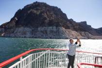 A passengers snaps photos during a mid-day sightseeing cruise of Lake Mead National Recreation ...