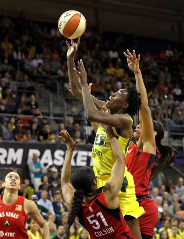 Seattle Storm's Natasha Howard, center, is fouled by Las Vegas Aces' Sydney Colson (51) as Aces ...