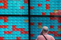 A man looks at an electronic stock board showing Japan's Nikkei 225 index at a securities firm ...