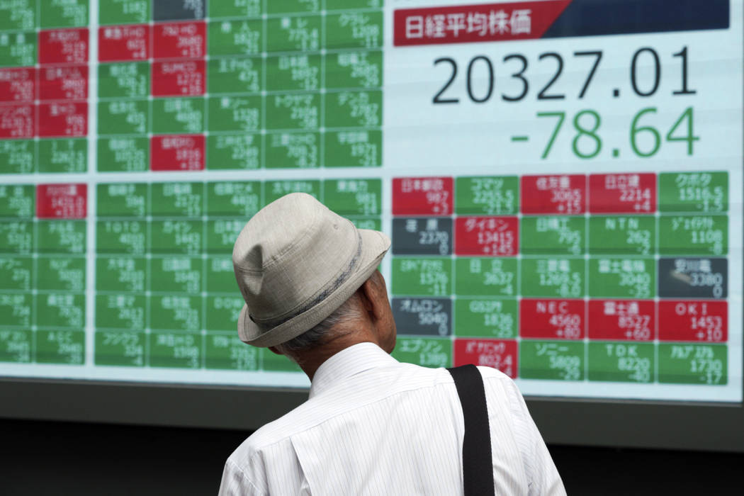 A man looks at an electronic stock board showing Japan's Nikkei 225 index at a securities firm ...