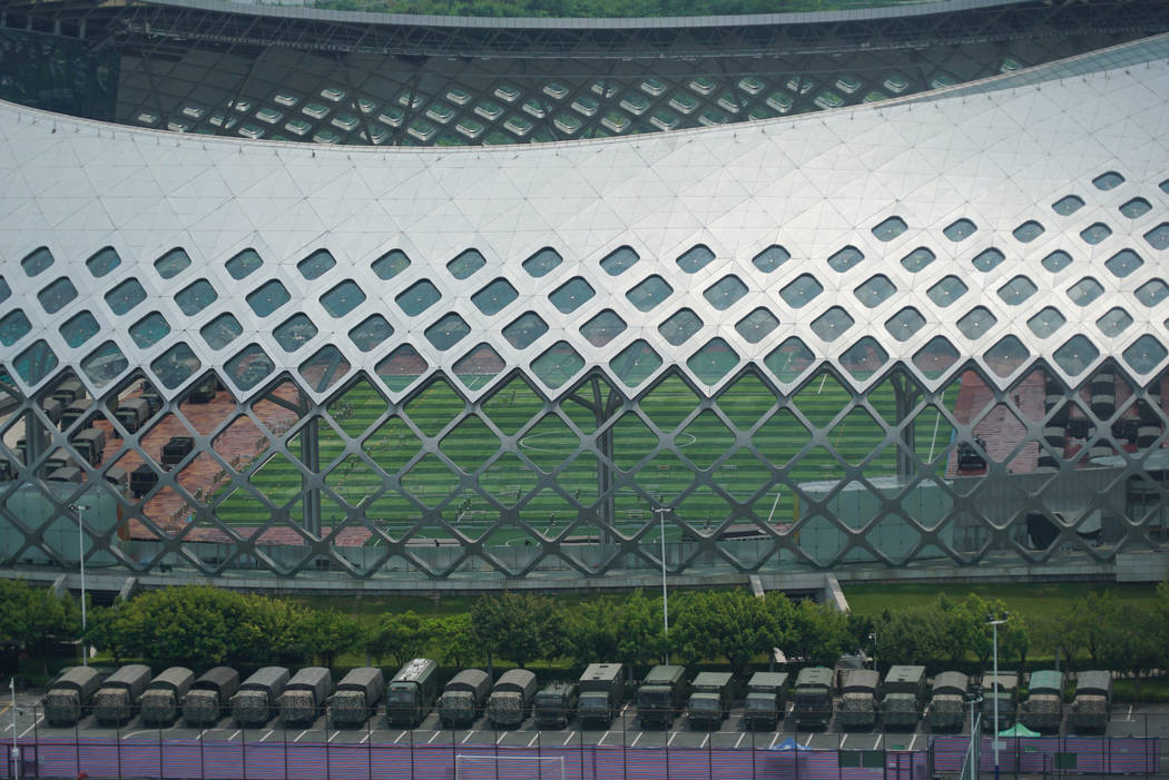 Armored vehicles and troop trucks are parked in a lot by Shenzhen Bay Stadium in Shenzhen, Chin ...