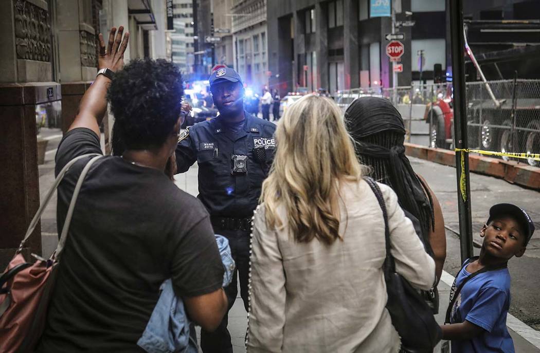 An NYPD anti-terror officer prevents pedestrians to pass, as police seal off area in the financ ...