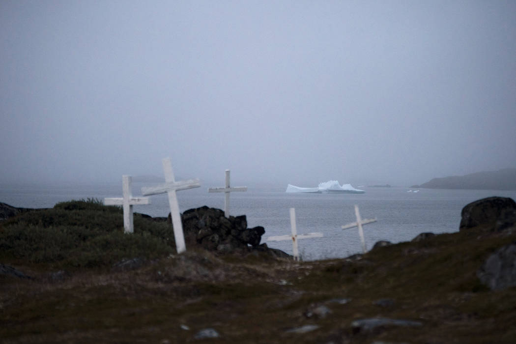 An iceberg floats near a cemetery in Kulusuk, Greenland, early Thursday, Aug. 15, 2019. Greenla ...