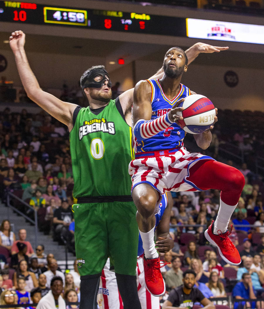 Harlem Globetrotter Bulldog Mack (5, right) soars past the Washington Generals Cager (0) to the ...