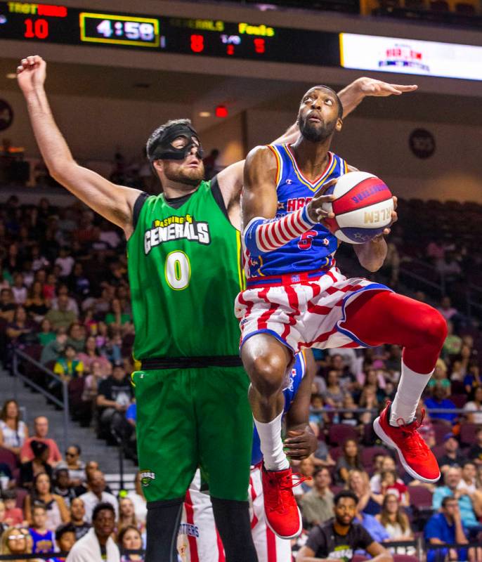 Harlem Globetrotter Bulldog Mack (5, right) soars past the Washington Generals Cager (0) to the ...