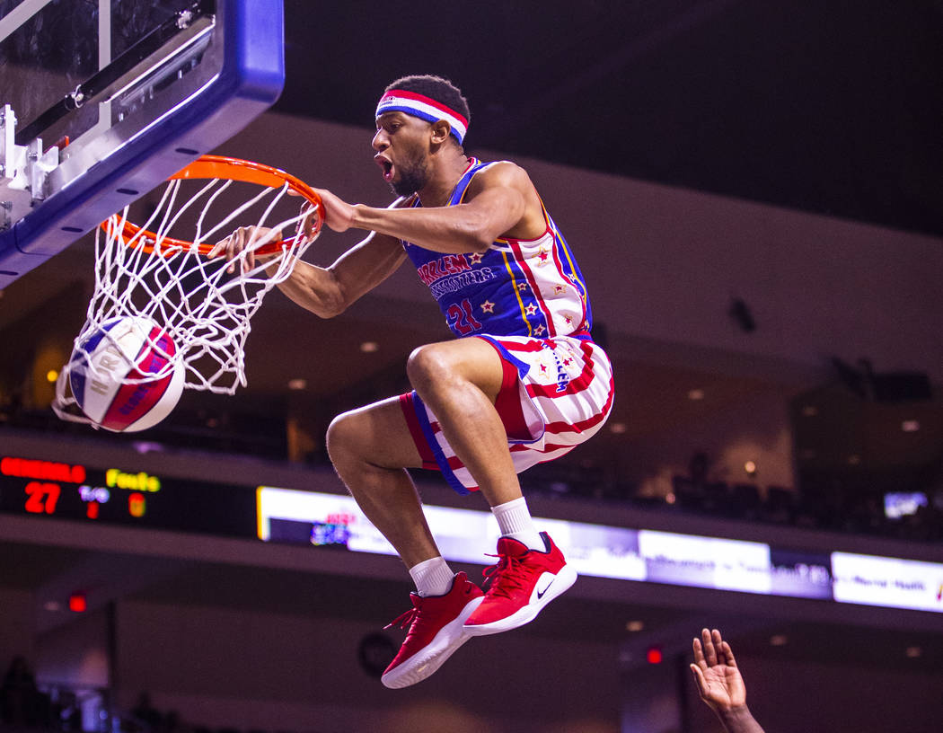 Harlem Globetrotter Lights Out Lee (21) soars above the rim for a dunk with a lift from teammat ...