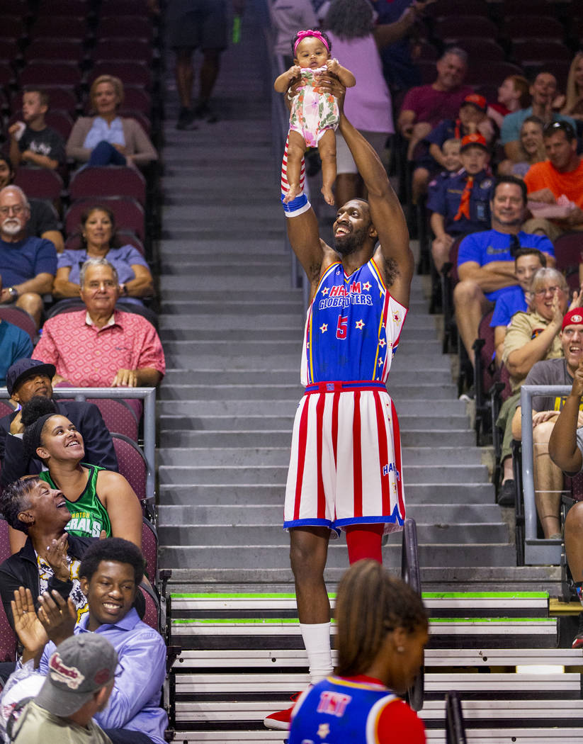 Harlem Globetrotter Bulldog Mack (5) holds up Kaia Johnson, 4 months old, in a parody of "The L ...