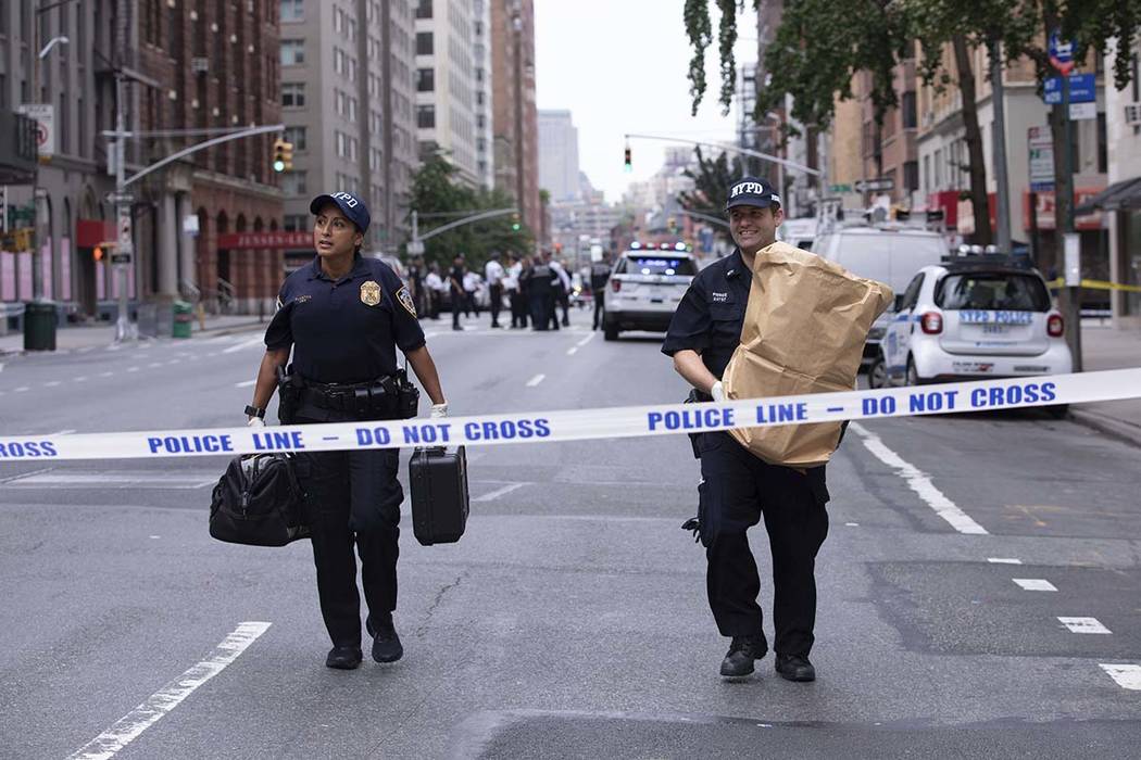 An investigator carries away a suspicious package as evidence after it was thought to be an exp ...