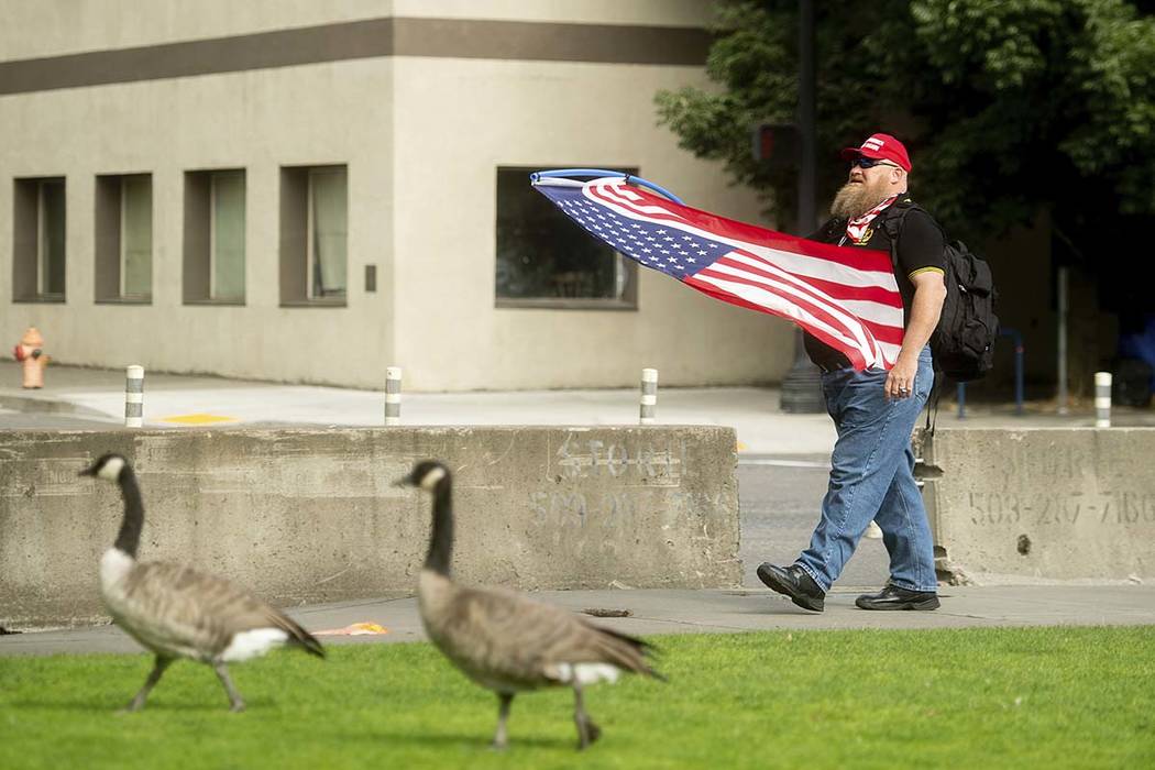 A member of the Proud Boys, who declined to give his name, carries a flag before the start of a ...