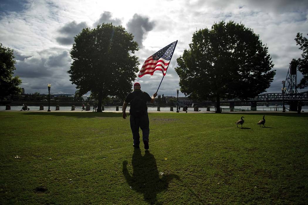 A member of the Proud Boys, who declined to give his name, carries a flag before the start of a ...