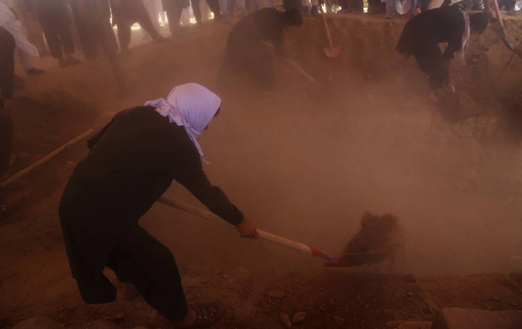 Afghans fill the graves of victims of the Dubai City wedding hall bombing during a mass funeral ...