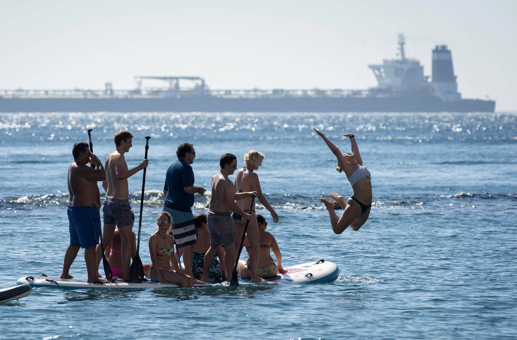 Renamed Adrian Aryra 1 super tanker is seen in background as people cool-off in the water in th ...