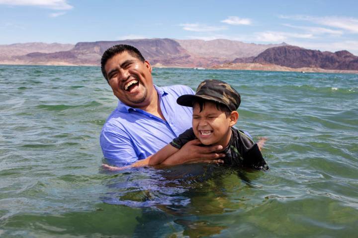 Pastor Erasmo Solis laughs while teaching his son Girsom Solis how to swim at Boulder Beach on ...