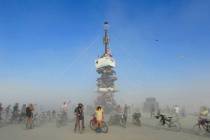 Burners are surrounded by playa dust climb onto an art installation titled, "Night of the Climb ...