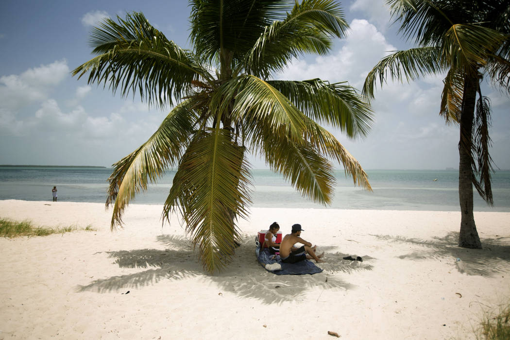 In a July 1, 2015, file photo, Marvin Hernandez, right, and Kelly Vera sit in the shade of a pa ...