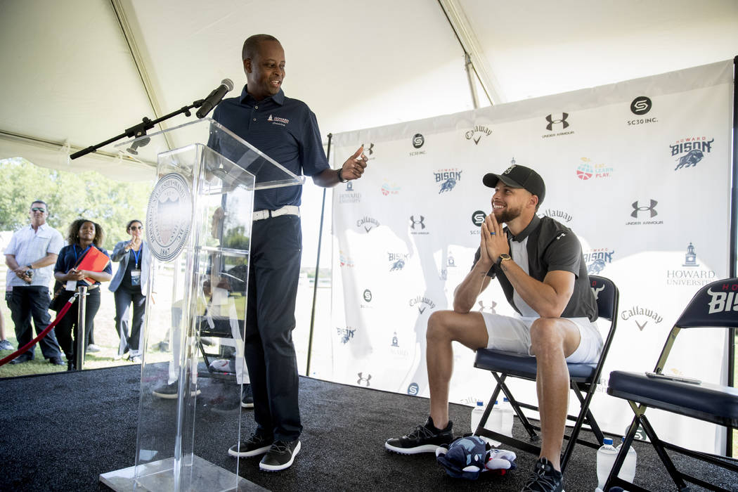 Howard University president Wayne Frederick, left, looks at Golden State Warriors guard Stephen ...