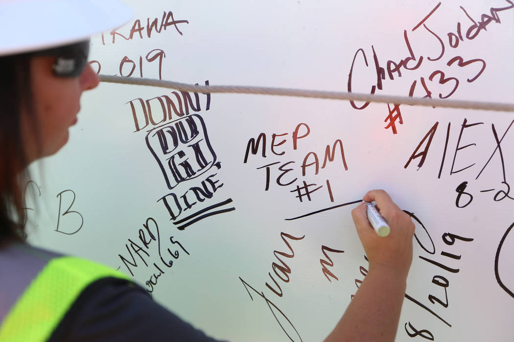 Project Engineer Kristy Staff signs the last high steel beam before it is hoisted on top of the ...