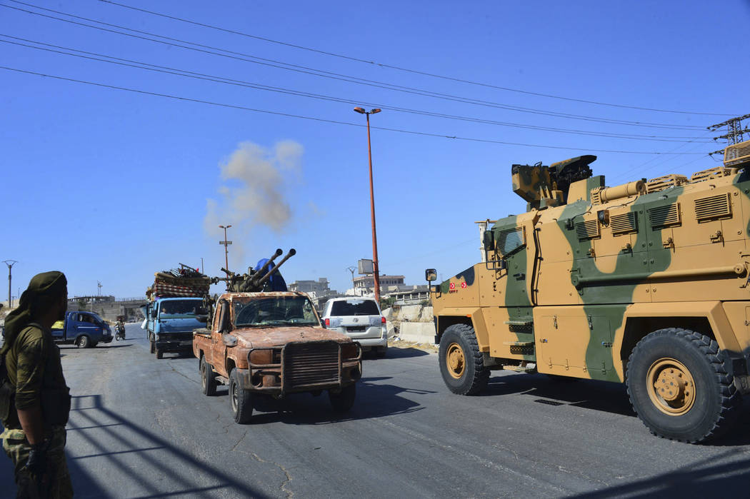 Smoke rises in the background from bombardment around the area as fighters with the Free Syrian ...