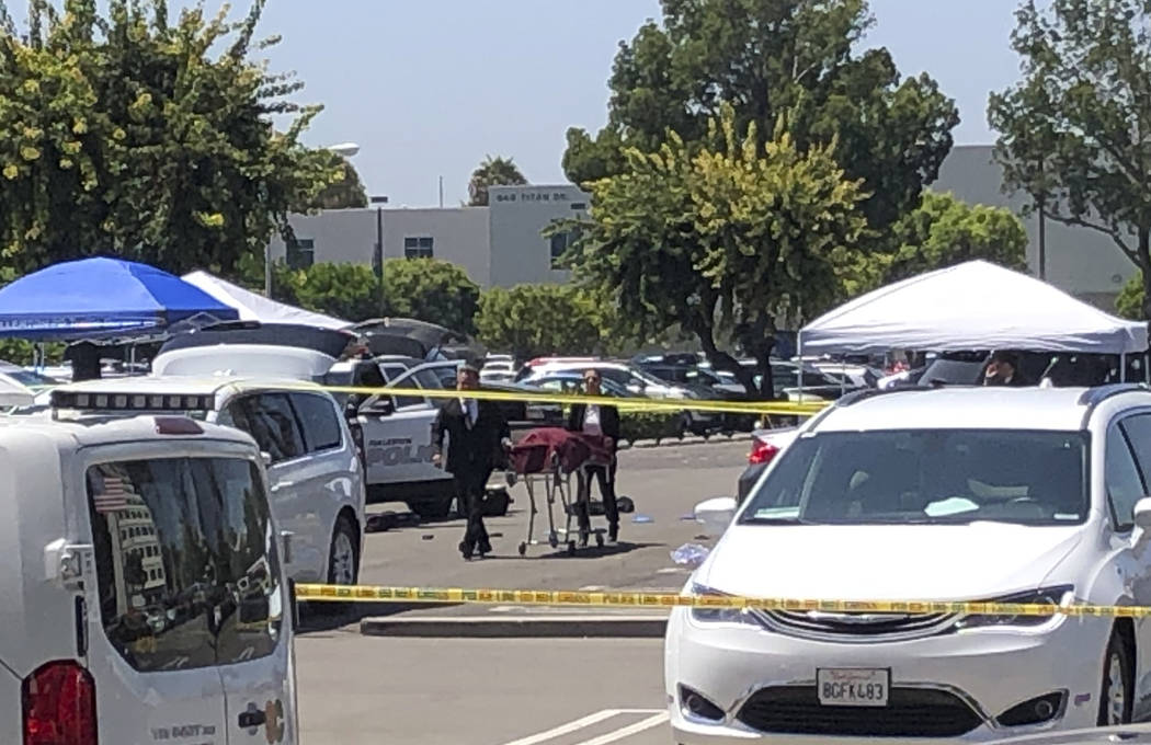 Orange County coroners remove a body of a stabbing victim from a parking lot from a parking lot ...