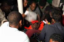 A woman is assisted following a panic attack onboard the Open Arms vessel in front of island of ...