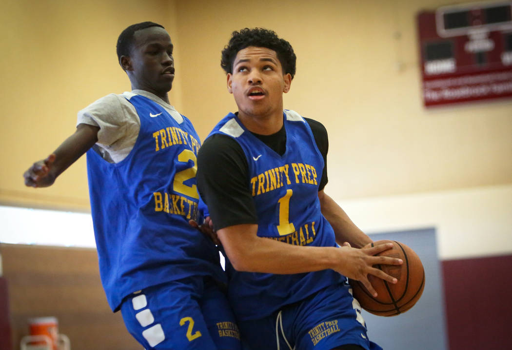 Trinity International junior Daishen Nix, right, drives past teammate Madait Mou during a pract ...