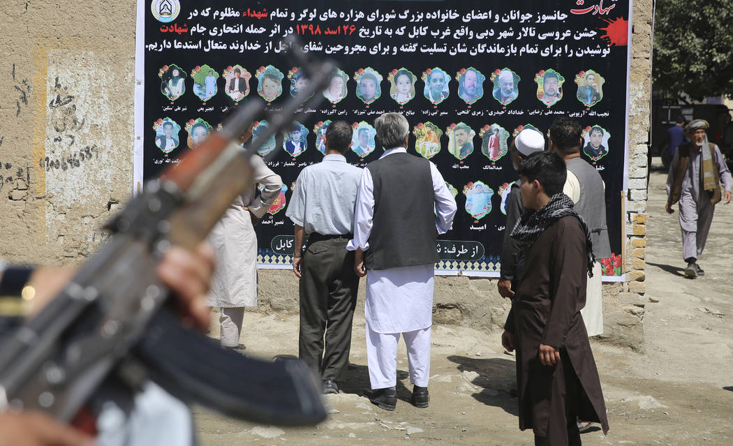 Afghans look at a banner displaying photographs of victims of the Dubai City wedding hall bombi ...