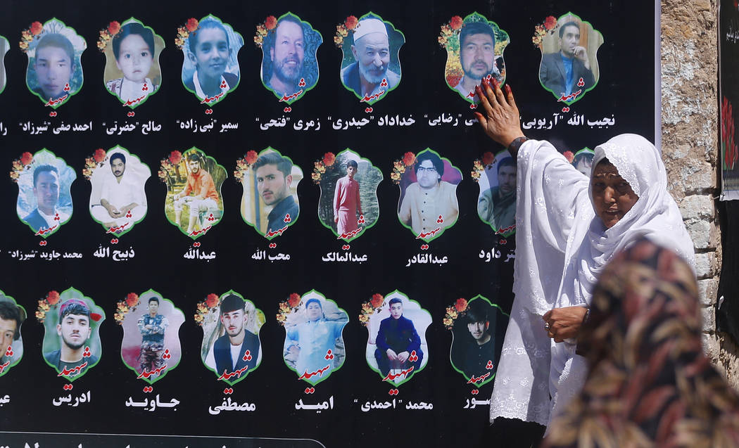 An Afghan woman cries as she touches a banner displaying photographs of victims of the Dubai Ci ...