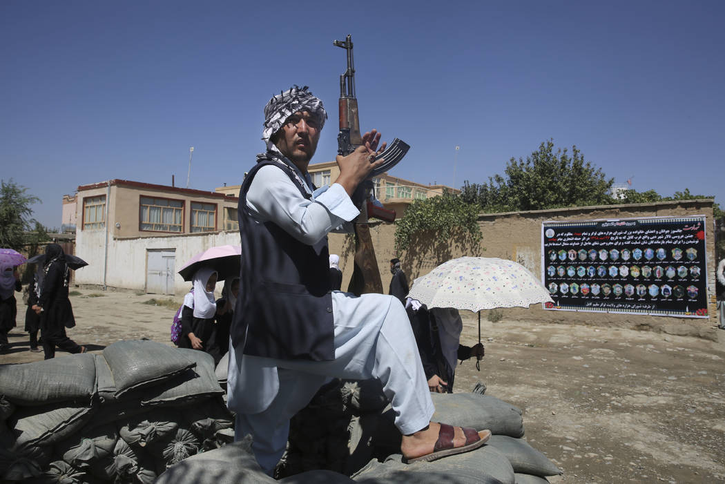 An Afghan volunteer stands guard outside a mosque during a memorial service for the victims of ...