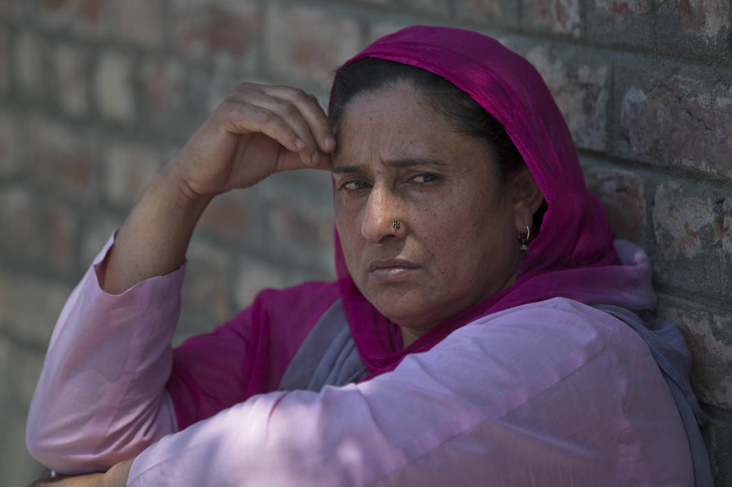 A Kashmiri woman sits on a footpath outside a police station waiting to hear the news about her ...