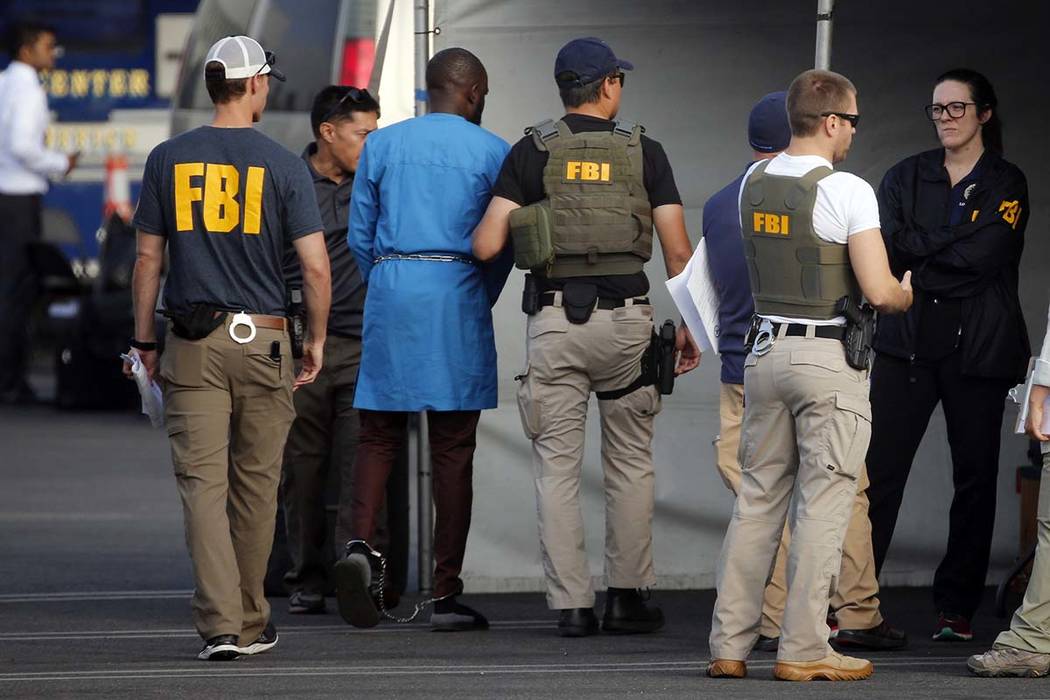 Federal agents hold a detainee, second from left, at a downtown Los Angeles parking lot after p ...