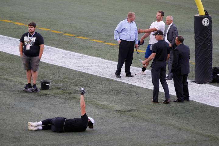 Officials assess the location where the CFL goal post holes were, before an NFL preseason footb ...