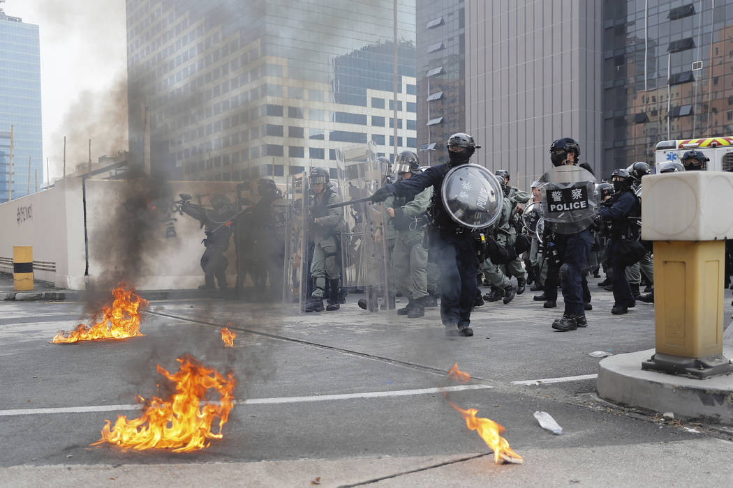 Riot police gather around small fires during a protest in Hong Kong, Saturday, Aug. 24, 2019. C ...