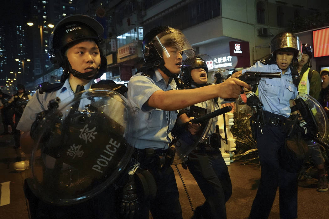 Policemen pull out their guns after a confrontation with demonstrators during a protest in Hong ...