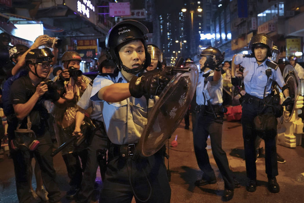 A policeman points his gun after confronting demonstrators during a protest in Hong Kong, Sunda ...