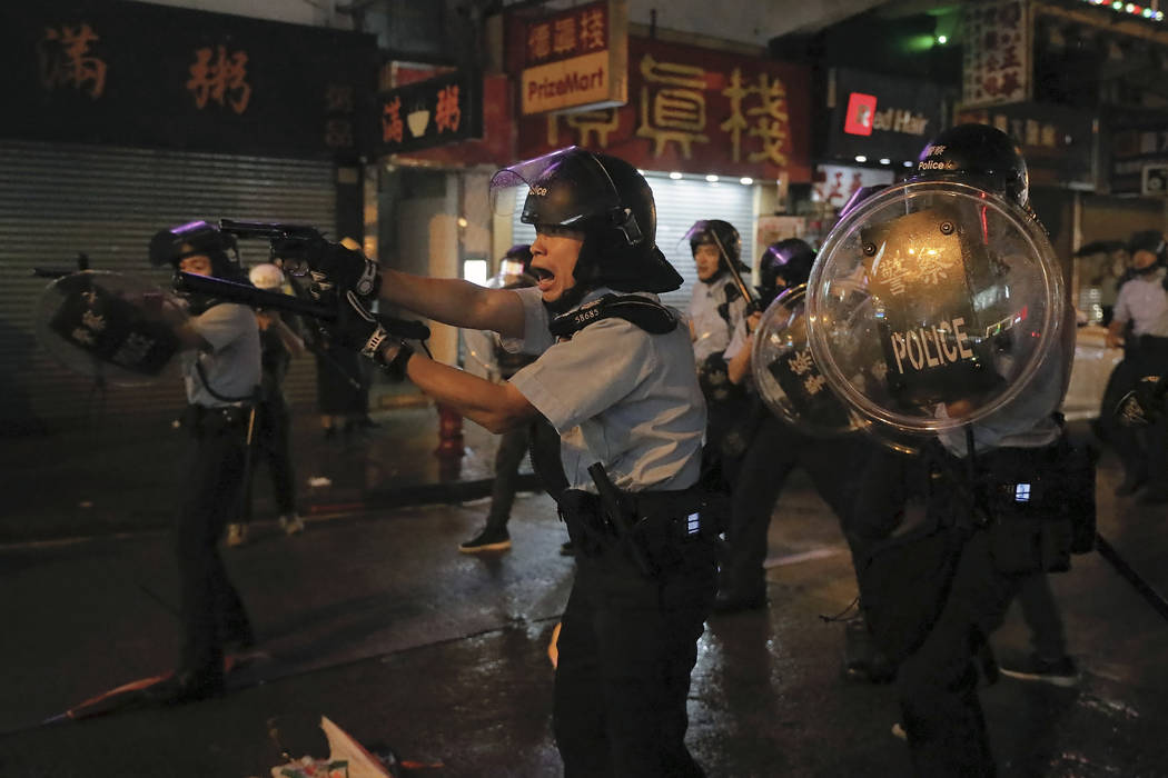 Policemen pull out their guns after a confrontation with demonstrators during a protest in Hong ...