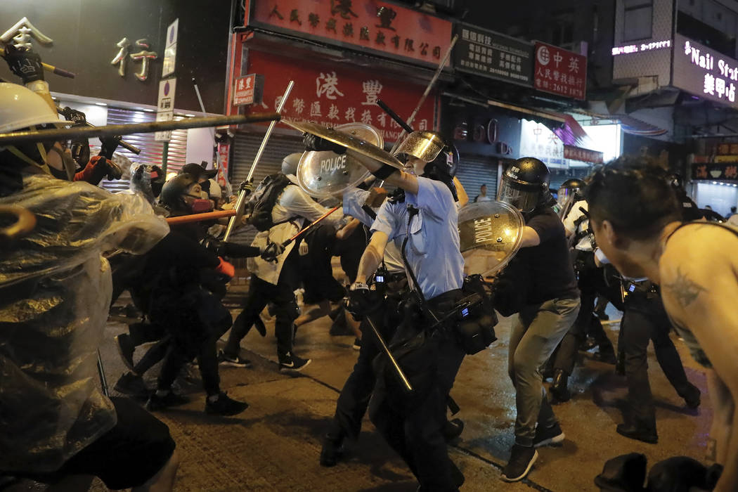 Policemen clash with demonstrators on a street during a protest in Hong Kong, Sunday, Aug. 25, ...